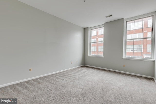 carpeted spare room featuring visible vents and baseboards
