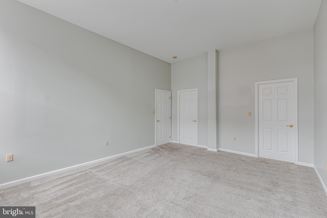 carpeted empty room featuring baseboards and a high ceiling