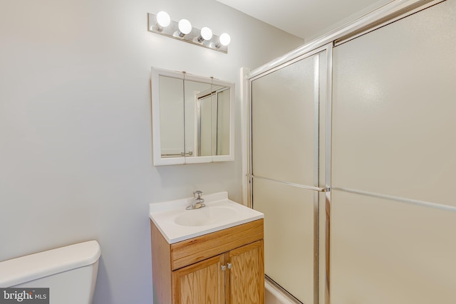 full bathroom with toilet, vanity, and a shower with door