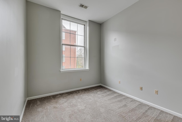 empty room with carpet, visible vents, and baseboards