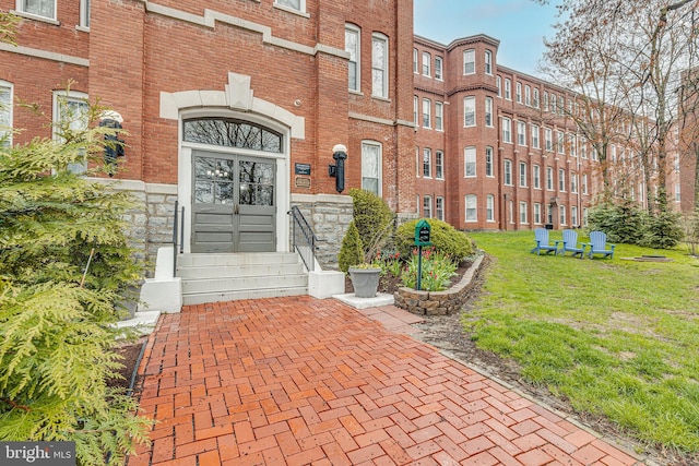 entrance to property featuring a yard and brick siding