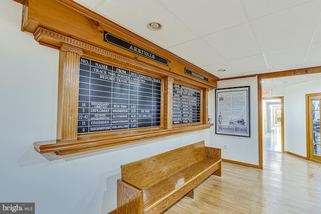 interior space with a paneled ceiling, baseboards, and wood finished floors