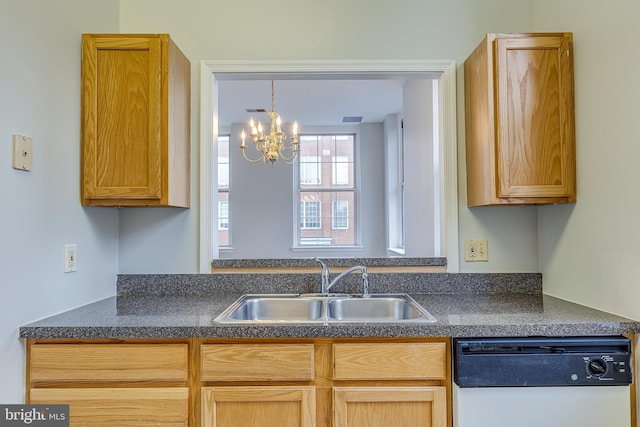 kitchen with dark countertops, a sink, white dishwasher, and a notable chandelier