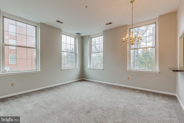 carpeted empty room featuring baseboards, a notable chandelier, and visible vents