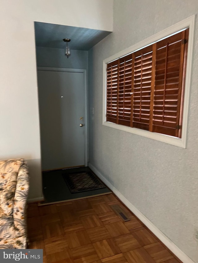 hallway featuring baseboards and visible vents