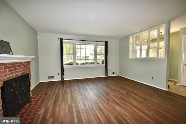 unfurnished living room featuring visible vents, baseboards, wood finished floors, and a fireplace
