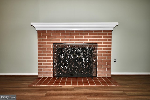 details featuring baseboards, wood finished floors, and a tile fireplace