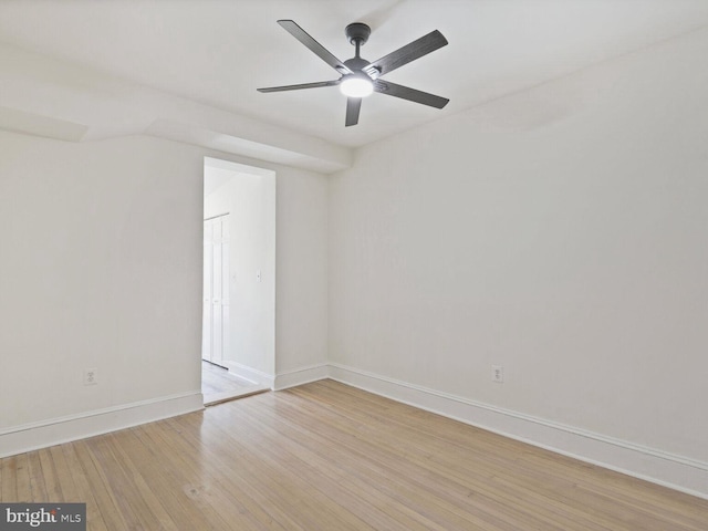 spare room with light wood-type flooring, a ceiling fan, and baseboards