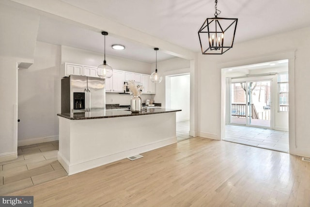kitchen featuring white cabinets, stainless steel fridge with ice dispenser, visible vents, light wood-type flooring, and baseboards