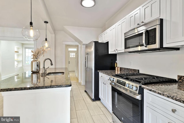 kitchen featuring a wealth of natural light, dark stone countertops, stainless steel appliances, and a sink