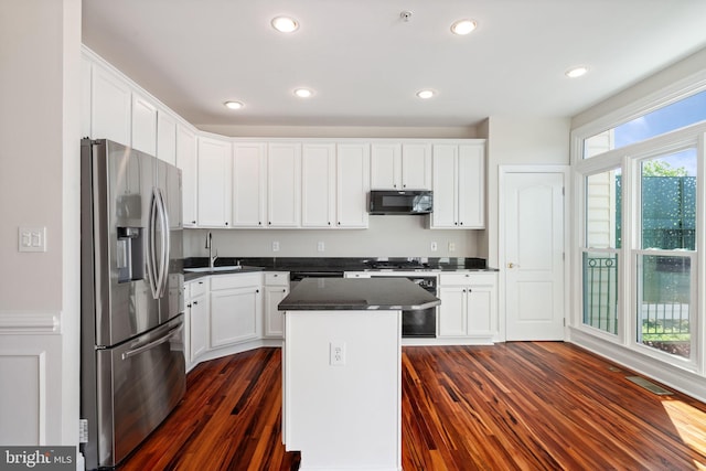 kitchen with black microwave, stainless steel fridge, a sink, stove, and dark wood-type flooring