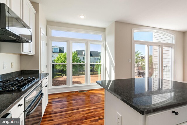 kitchen featuring white cabinetry, dark wood-style floors, black appliances, and dark stone countertops
