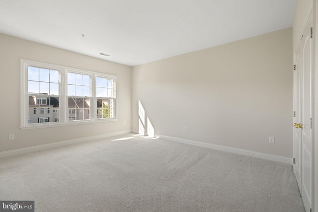 empty room with baseboards, visible vents, and light colored carpet