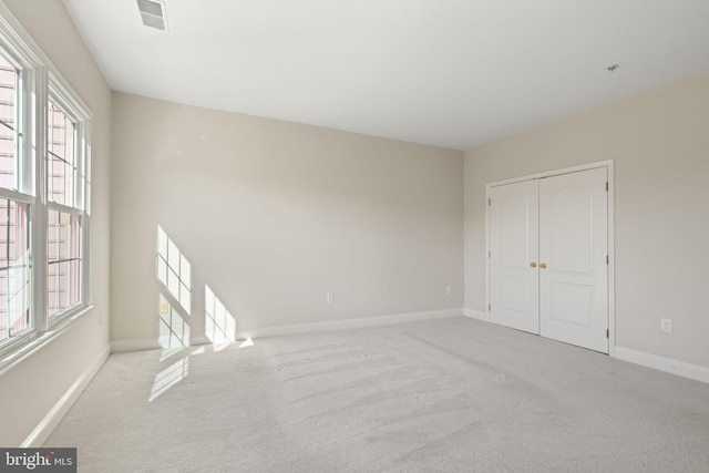 carpeted empty room with baseboards, visible vents, and plenty of natural light
