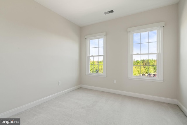 empty room featuring light colored carpet, baseboards, and visible vents