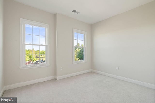 spare room with baseboards, a wealth of natural light, carpet, and visible vents