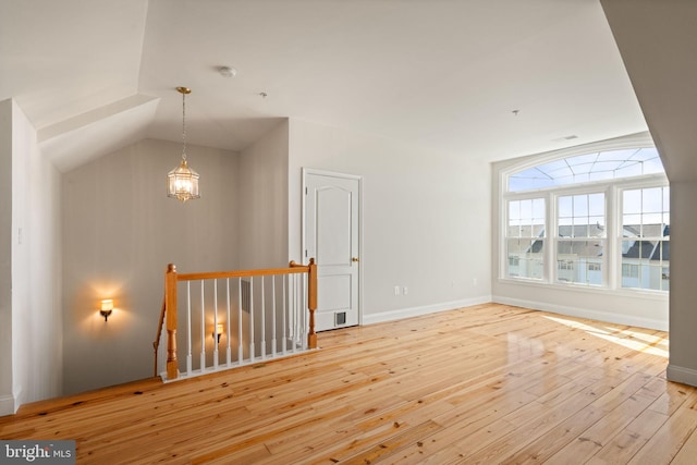 interior space with wood-type flooring, baseboards, and vaulted ceiling
