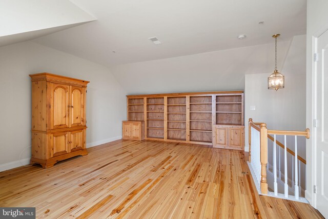 additional living space featuring light wood-style floors, baseboards, and lofted ceiling