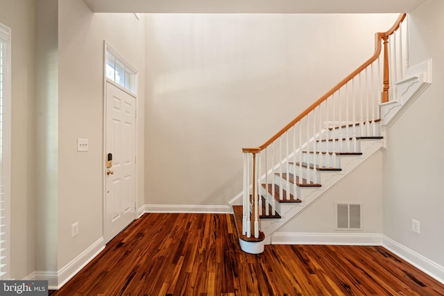 foyer featuring visible vents, wood finished floors, and stairway