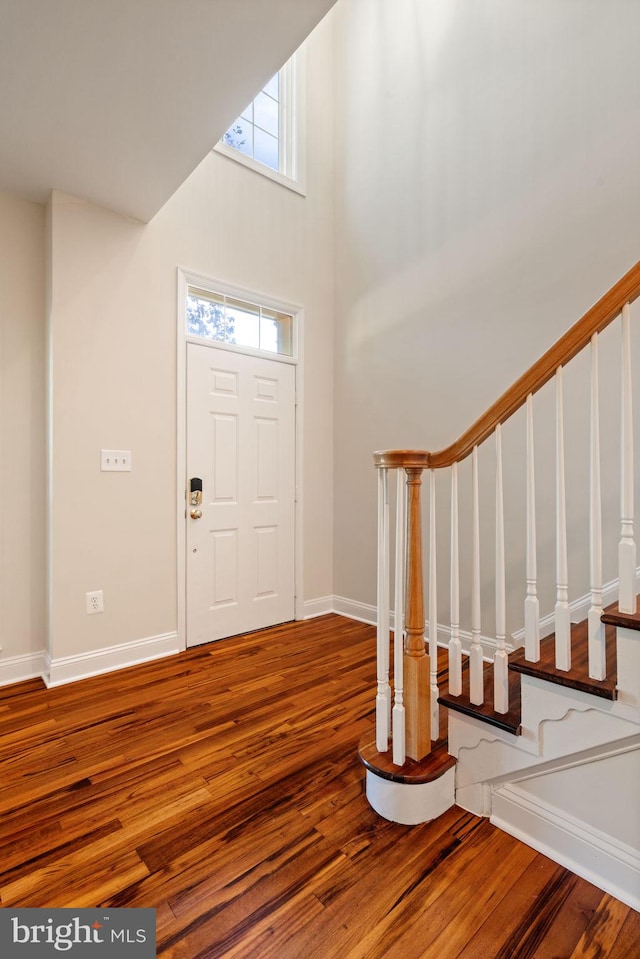 entrance foyer with baseboards, a high ceiling, stairs, and wood finished floors