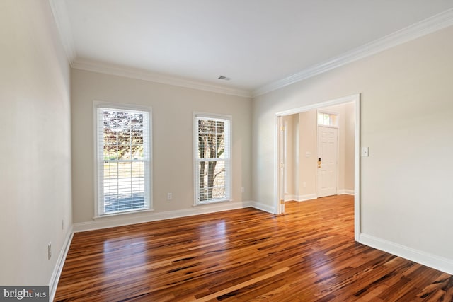 empty room with baseboards, ornamental molding, wood finished floors, and visible vents