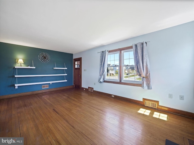 unfurnished living room with visible vents, baseboards, and hardwood / wood-style floors