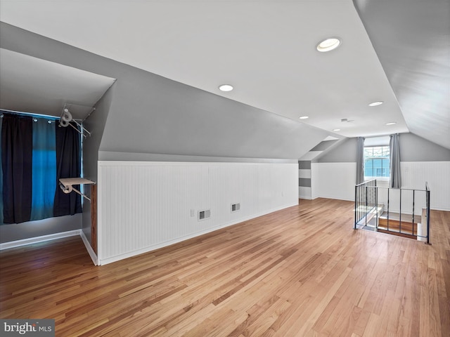 additional living space with visible vents, hardwood / wood-style flooring, and vaulted ceiling