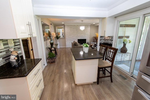 13909 Broomall Ln, Silver Spring, MD 20906 - kitchen featuring a breakfast bar area, backsplash, a large fireplace, and light wood-style floors