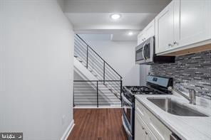kitchen with appliances with stainless steel finishes, light countertops, dark wood finished floors, and white cabinets