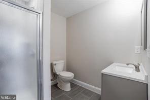 bathroom featuring a shower stall, vanity, baseboards, and toilet