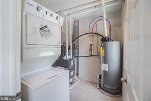 clothes washing area featuring water heater, stacked washer / dryer, and laundry area