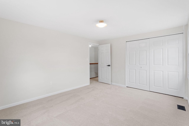 unfurnished bedroom with baseboards, carpet flooring, visible vents, and a closet
