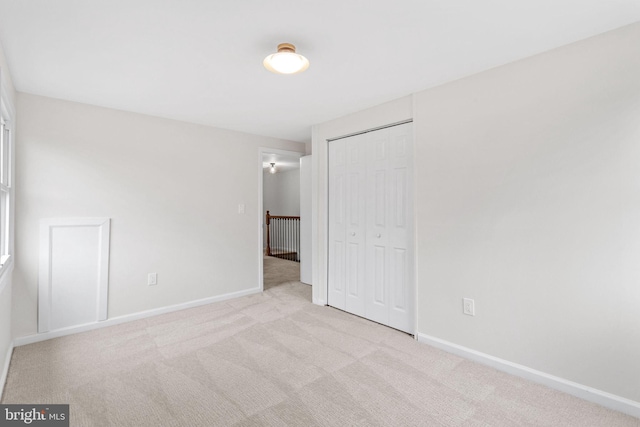 unfurnished bedroom with carpet floors, a closet, and baseboards