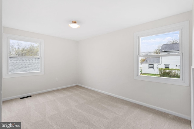 unfurnished room with visible vents, light carpet, and baseboards