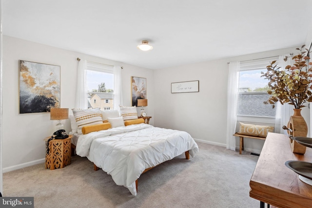 bedroom featuring baseboards, light colored carpet, and multiple windows