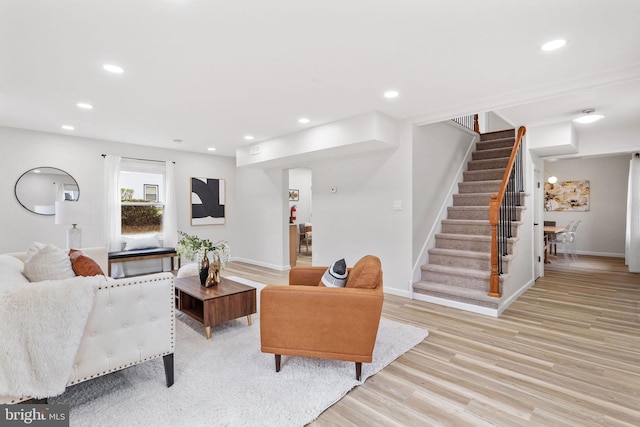 living room with light wood-type flooring, baseboards, recessed lighting, and stairs