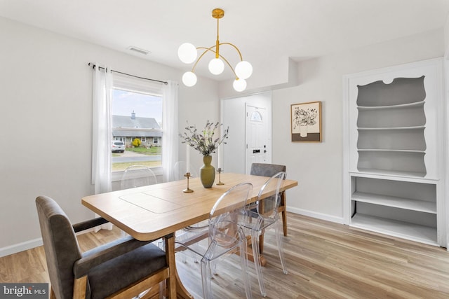 dining area featuring light wood-style floors, visible vents, baseboards, and a notable chandelier