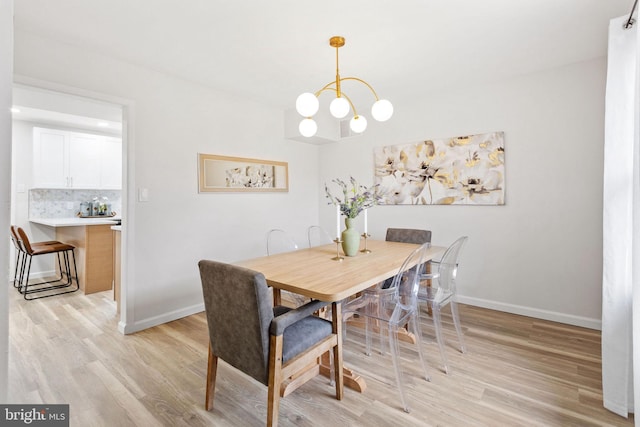 dining room featuring baseboards, an inviting chandelier, and light wood-style flooring