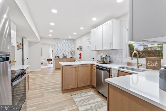 kitchen featuring recessed lighting, a peninsula, stainless steel appliances, and a sink