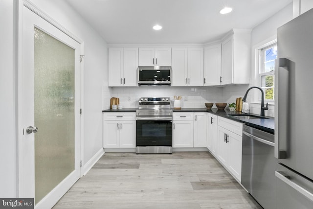 1302 Ashbridge Rd, West Chester, PA 19380 - kitchen featuring appliances with stainless steel finishes, a sink, white cabinets, light wood-style flooring, and dark countertops