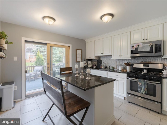 kitchen with backsplash, white cabinets, light tile patterned floors, and stainless steel appliances