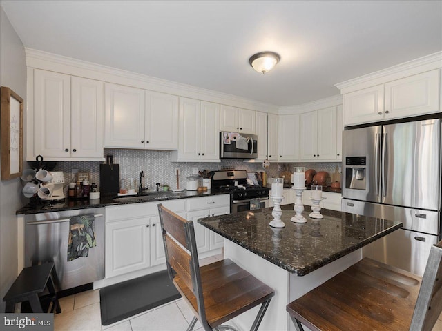 kitchen featuring tasteful backsplash, light tile patterned floors, white cabinets, a sink, and appliances with stainless steel finishes