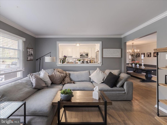living room with wood finished floors, an inviting chandelier, and ornamental molding