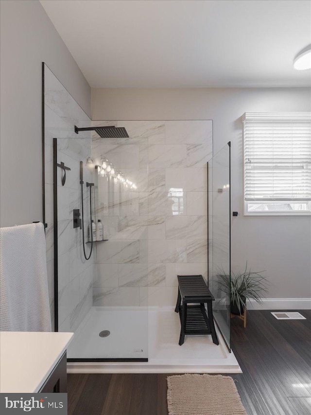 full bath with a walk in shower, vanity, baseboards, and wood finished floors