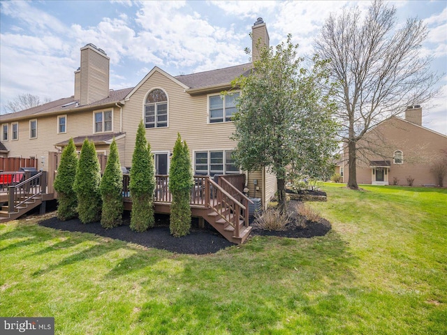 rear view of property featuring a wooden deck and a lawn