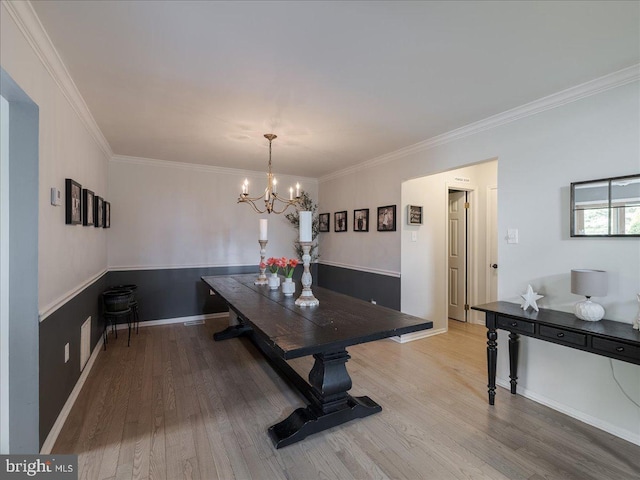 dining space with crown molding, wood finished floors, an inviting chandelier, and baseboards
