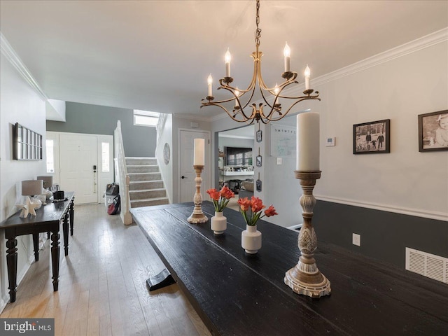 dining room featuring light wood-style flooring, crown molding, visible vents, and stairway