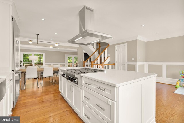 6660 Kelsey Point Cir, Alexandria, VA 22315 - kitchen with stainless steel gas stovetop, island range hood, crown molding, white cabinetry, and light wood-style flooring
