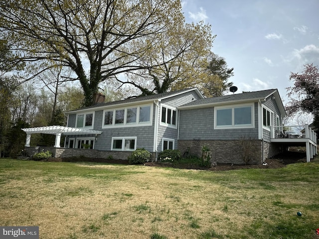back of property with a chimney, a wooden deck, a pergola, and a lawn
