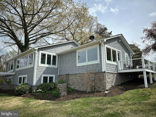 view of property exterior with a wooden deck, a lawn, and stone siding